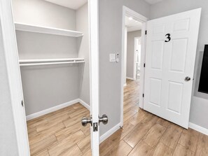 A hallway with a white door marked with the number 3, a white closet with a metal handle, and a light switch on the wall.