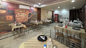 Een restaurant met meerdere tafels en stoelen, een plafondventilator en een muur met een muurschildering over koffie.