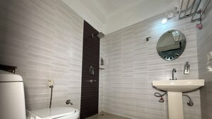 Een badkamer met toilet, wastafel, spiegel en douche.