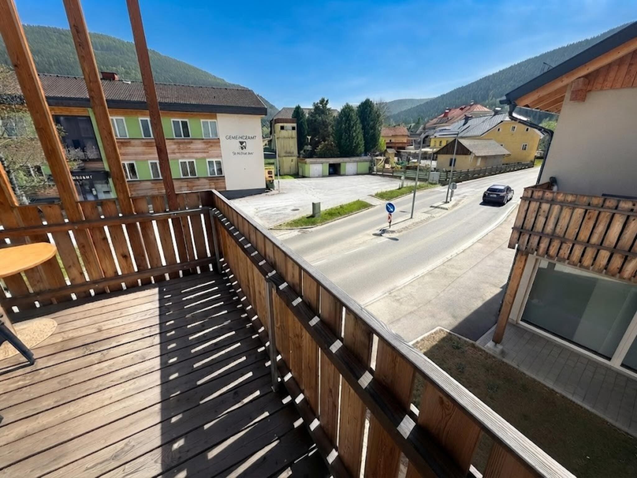 Una terraza de madera con vistas a una calle y edificios.