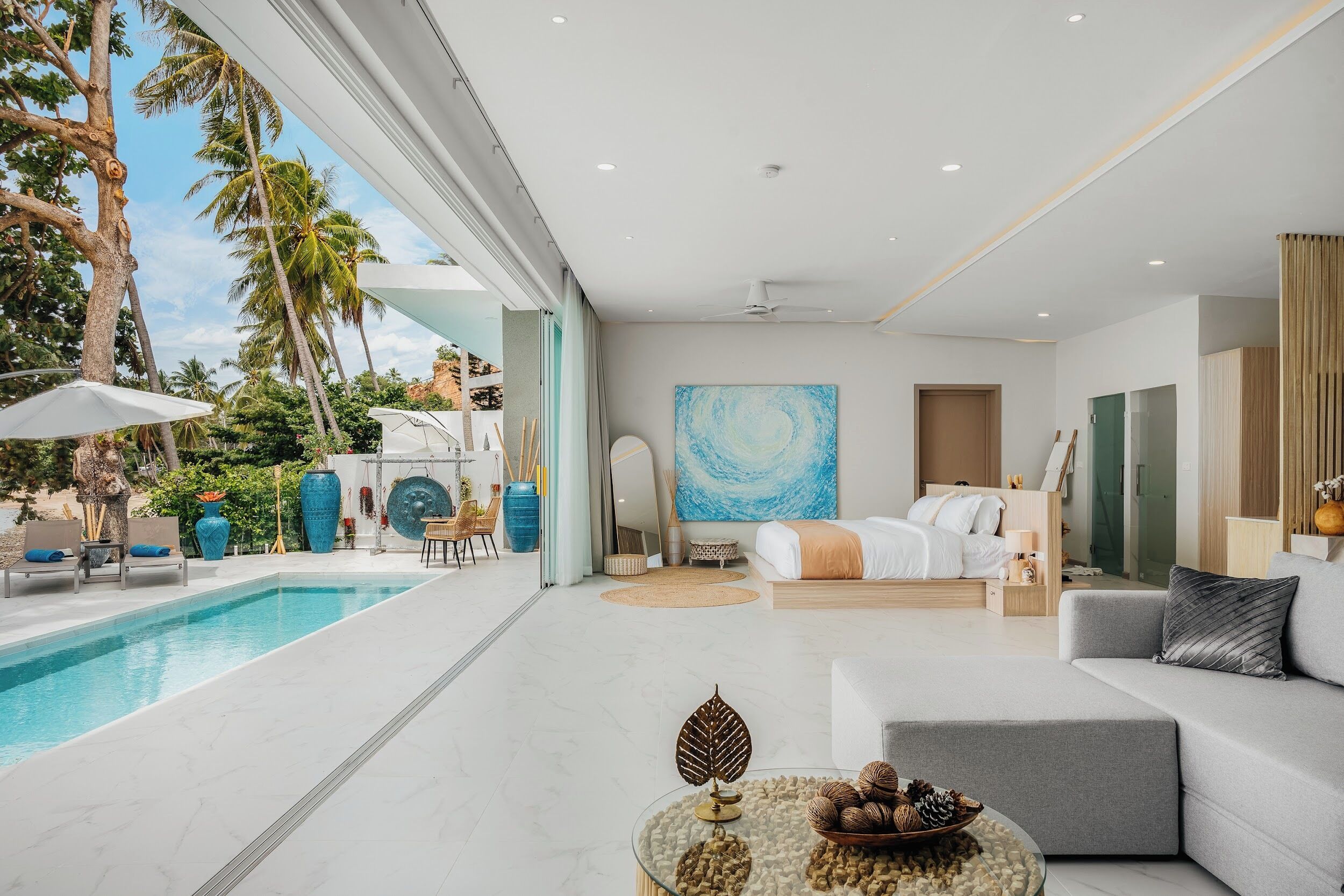 A modern hotel room with a pool, a sofa, a bed, and a large abstract painting.