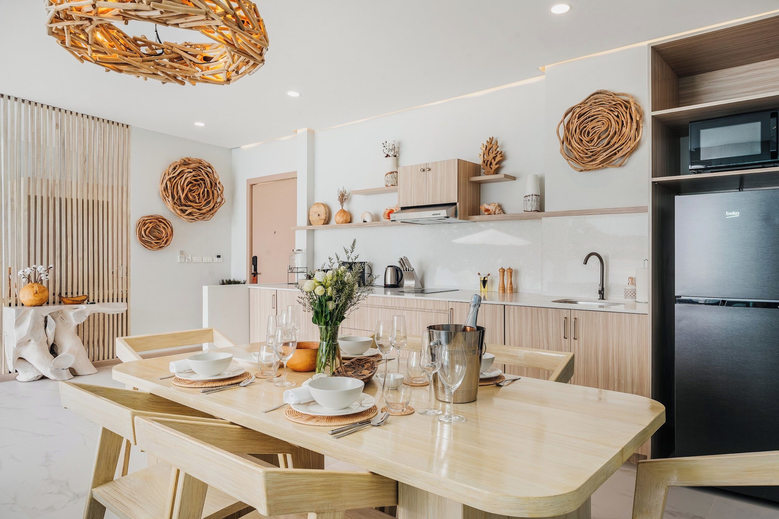 A modern kitchen with wooden cabinets, a black refrigerator, and a dining area with a wooden table set for six.