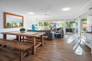 A spacious living area with a wooden dining table, benches, a sofa, and a large mirror on the wall. - The Hilltop Noosa Retreat: Walk to Beach + Pool (Noosa Region)