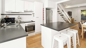 A modern kitchen with white cabinets, a black countertop, a built-in oven, and a refrigerator. - Relaxed Noosaville Living - Poolside & Walkable (Noosa Region)