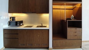 A compact kitchen with built-in appliances, a sink, and wooden cabinetry. - Panorama Luxury Hotel - Full Services (Nha Trang)