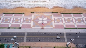 An aerial view of a beach with a patterned pavement and a road with vehicles. - Panorama Luxury Hotel - Full Services (Nha Trang)
