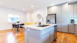 Una cucina moderna con mobili grigi, un'isola centrale con lavandino e un'area pranzo con sedie.