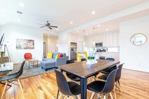 Una sala de estar moderna con comedor, cocina y ventilador de techo.