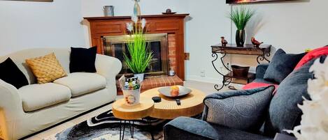 A living room with a fireplace, a sofa, a coffee table, and a TV mounted on the wall.