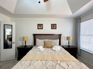 Un dormitorio con una cama, dos mesitas de noche, un cabecero, dos lámparas de pared y un ventanal con persianas.