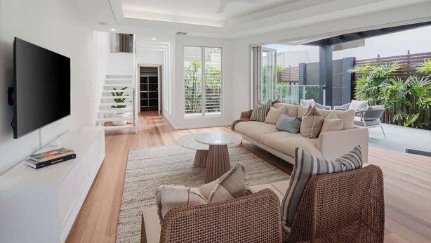 Una sala de estar moderna con un sofá, sillones de mimbre, una mesa de centro y un televisor.