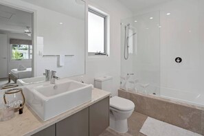 A modern bathroom with a large bathtub, a toilet, and a shower. - Modern, Airy Duplex Steps to River w/ Heated Pool (Noosa Region)
