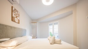A bedroom with a bed, bedside table, and a window with a view.