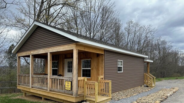 A small wooden cabin with a porch, a front door, and a sign that reads 'THE HEN HOUSE.' - Brand New! Bright, Airy Cabin Boarding Winslow Hill Elk Viewing Area! (Benezette)