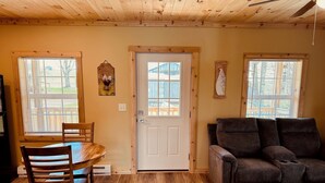 A wooden interior with a dining table, chairs, a sofa, and a door. - Brand New! Bright, Airy Cabin Boarding Winslow Hill Elk Viewing Area! (Benezette)