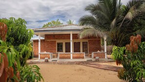 A brick building with a covered porch, surrounded by lush greenery. - Wild Edge Panama - Kumana Safari Lodge (Panama)