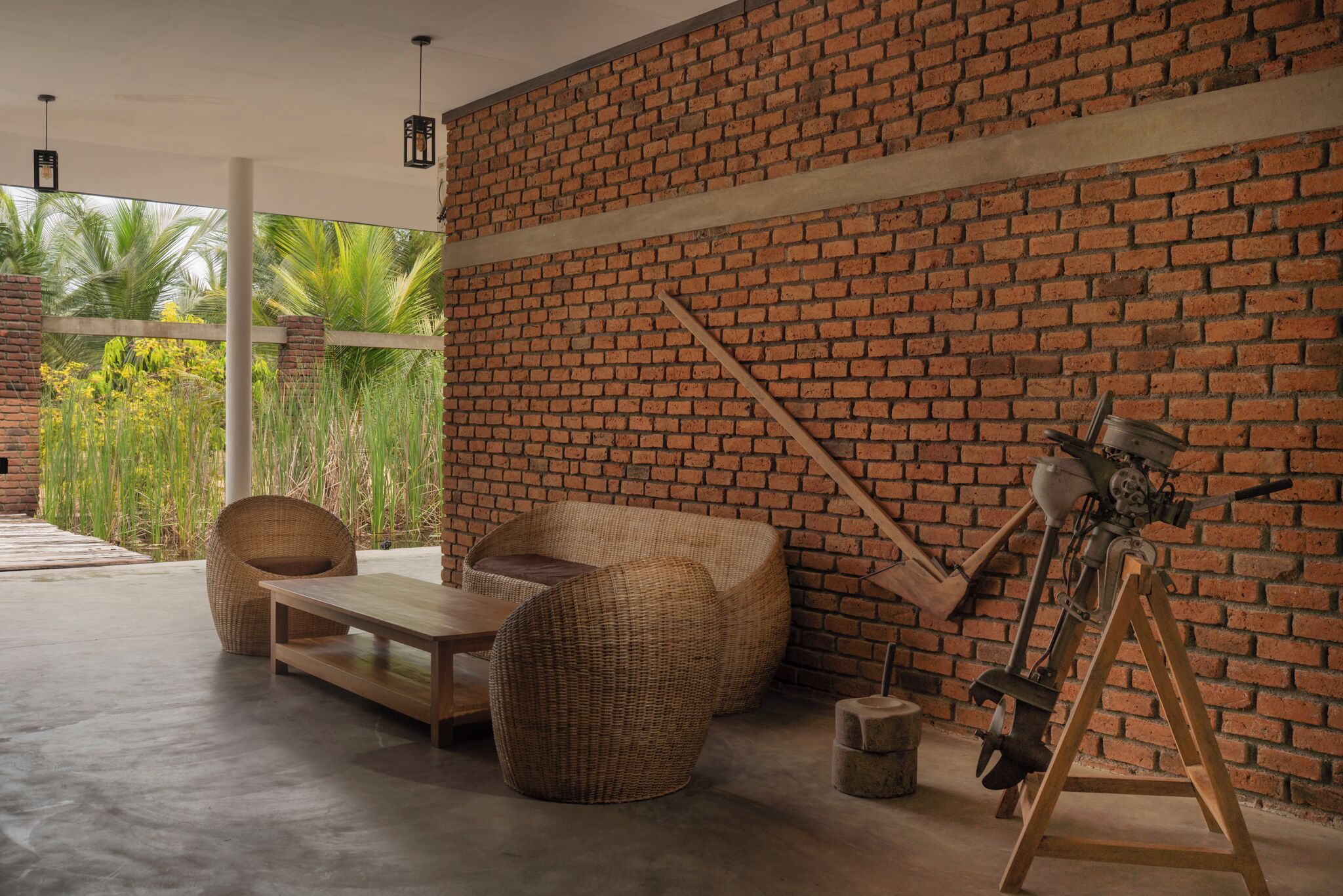 A room with a brick wall, wicker furniture, a wooden table, and a tripod.