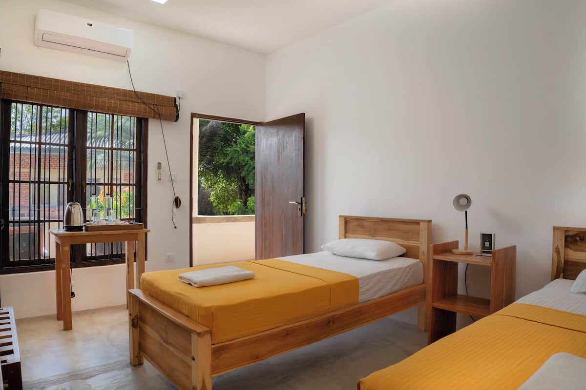 A bedroom with a bed, a desk, a chair, and a window.