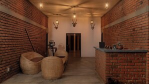 A room with brick walls, wicker furniture, antler wall decor, and a bar area. - Wild Edge Panama - Kumana Safari Lodge (Panama)