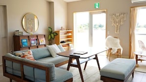 A modern living room with a sofa, ottoman, coffee table, and a bookshelf.