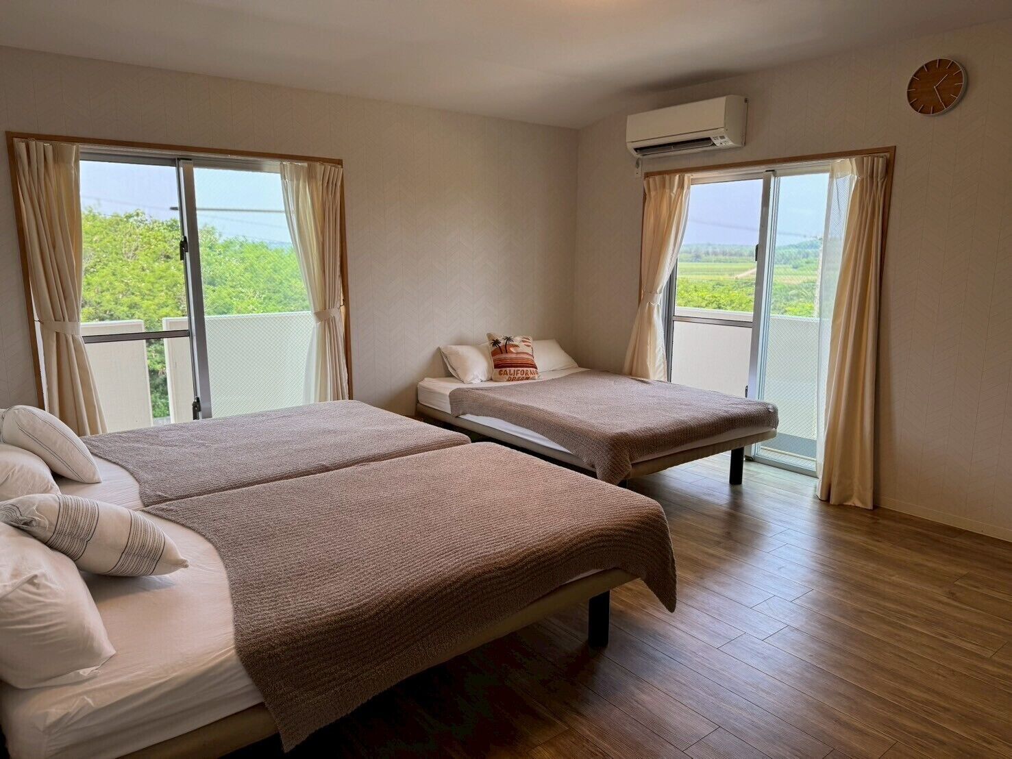 Habitación de hotel con dos camas, una ventana, unidad de aire acondicionado y vista a zonas verdes.