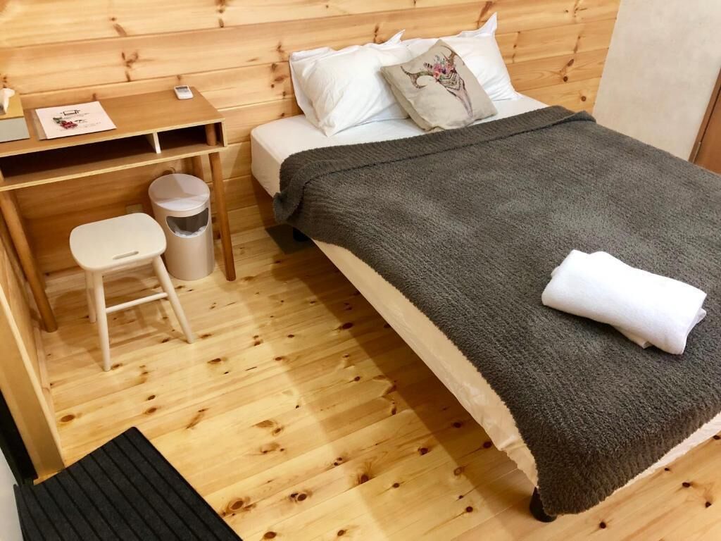 Una habitación de madera con una cama, un escritorio y un taburete pequeño.