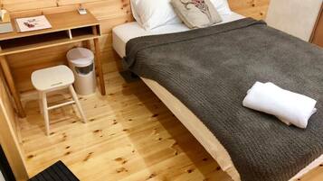 Una habitación de madera con una cama, un escritorio y un taburete pequeño.