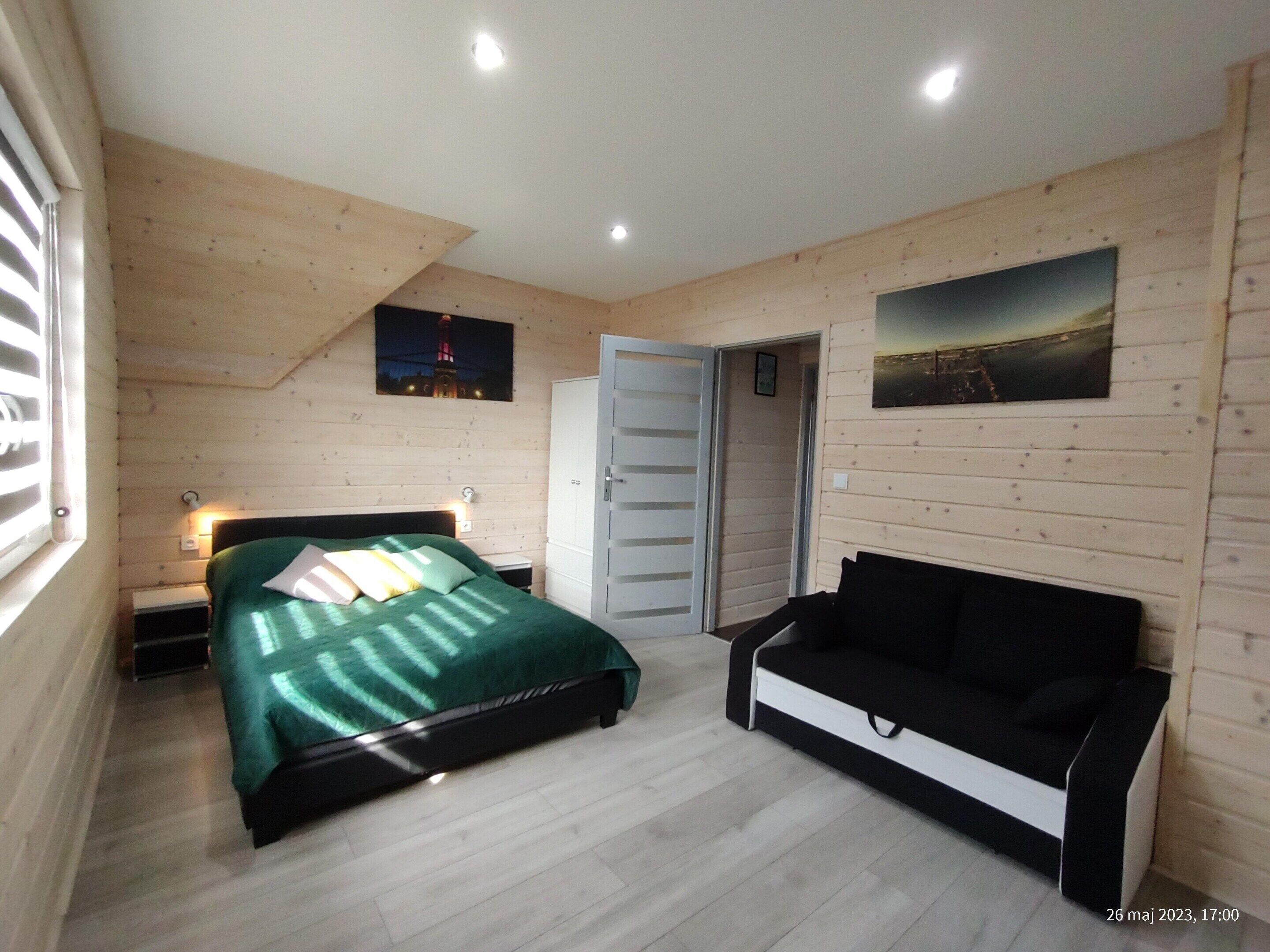 Ein Schlafzimmer mit Bett, Nachttisch, Kommode, einer Bank und zwei Bildern an der Wand.
