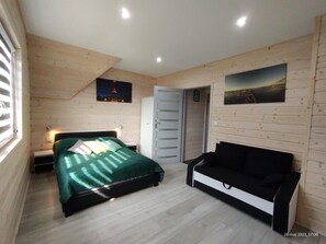 A bedroom with a bed, a nightstand, a dresser, a bench, and two wall-mounted pictures. - Holiday Home in Rewal Near the Beach (Rewal)