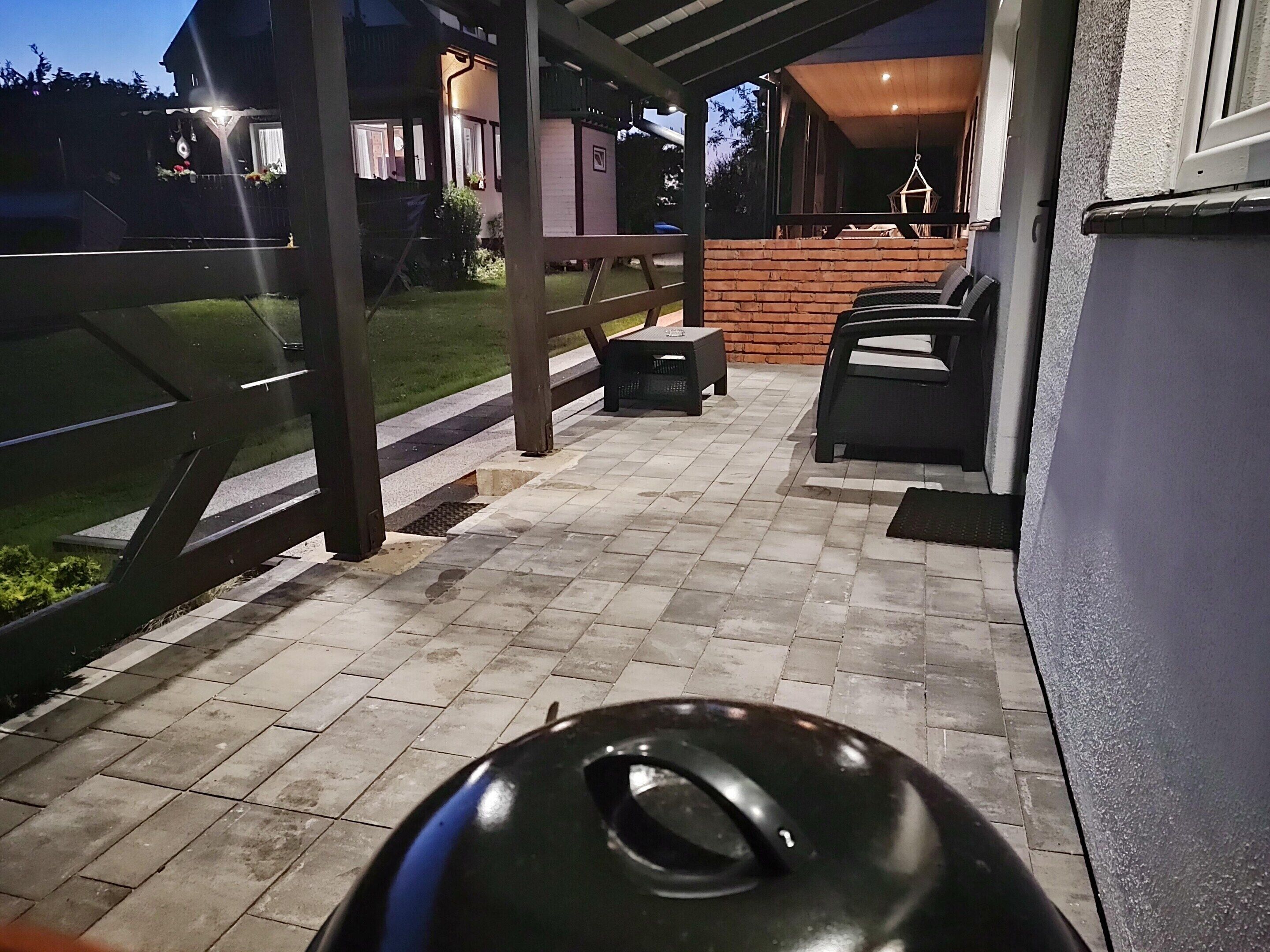 An outdoor patio area with a grill, seating, and a view of a house.