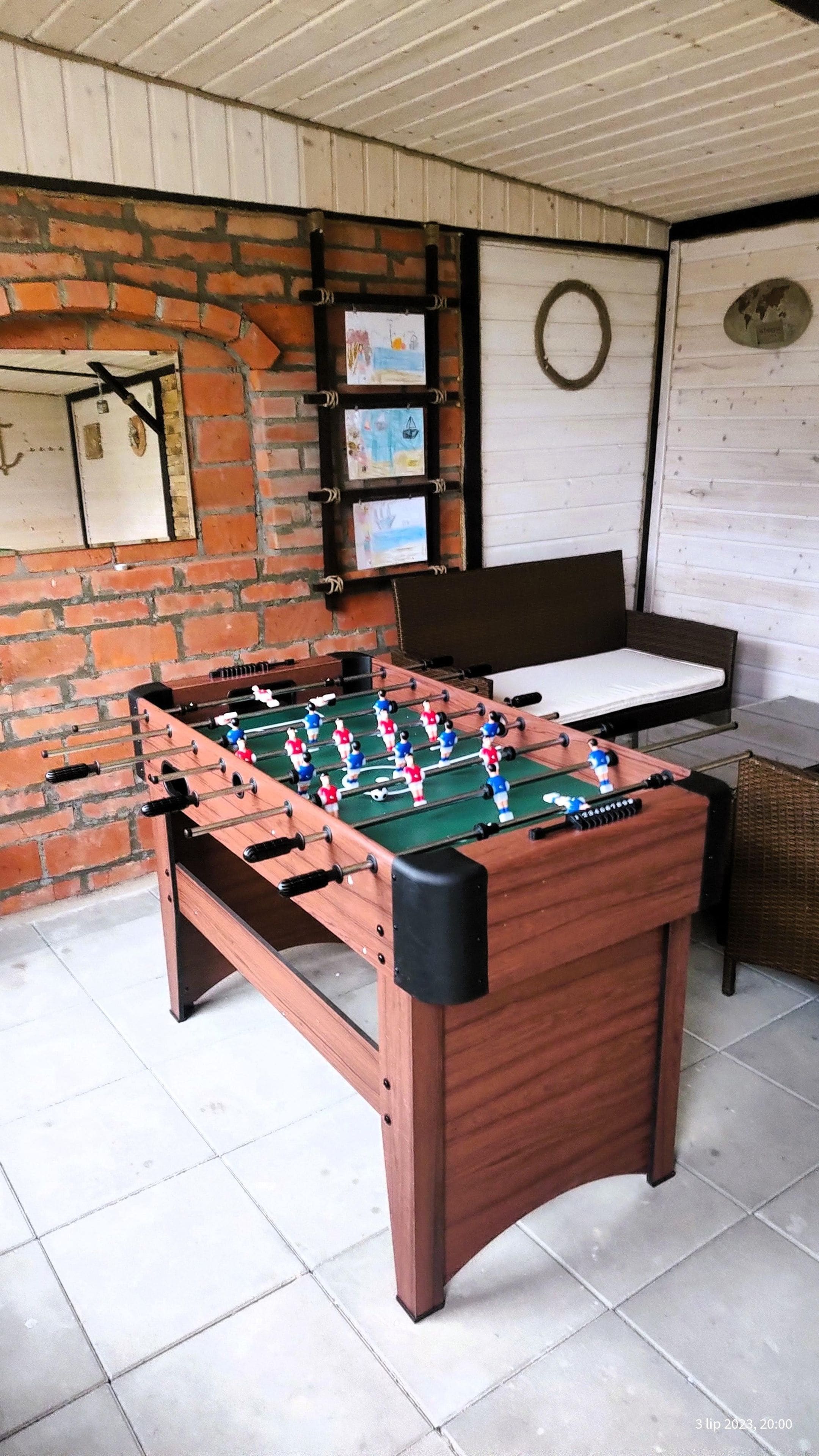 A foosball table in a room with a brick wall, a white door, and a white ceiling.
