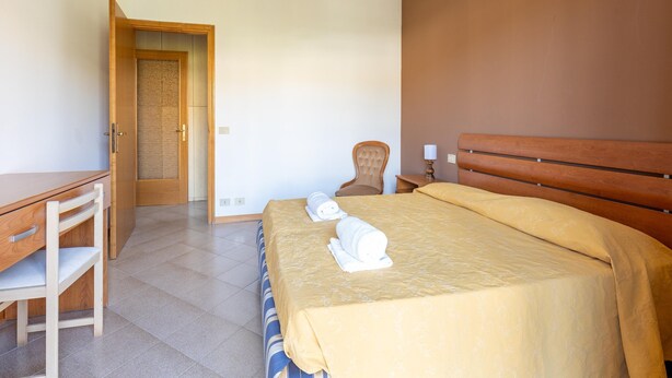 Een slaapkamer met een bed, een stoel, een bureau en een kroonluchter.