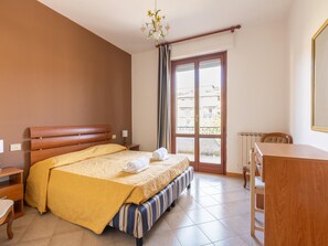 Ein Schlafzimmer mit einem Bett, einem Schreibtisch, einem Stuhl und einer Kommode.