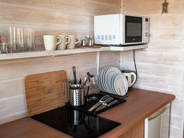 Una cocina con microondas, cafetera y varios utensilios sobre la encimera.