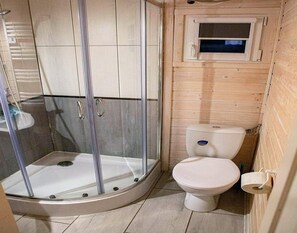 A bathroom with a glass-enclosed shower, a toilet, and a small window. - Holiday Home in Dziwnowek by Baltic Sea (Kamien Pomorski)