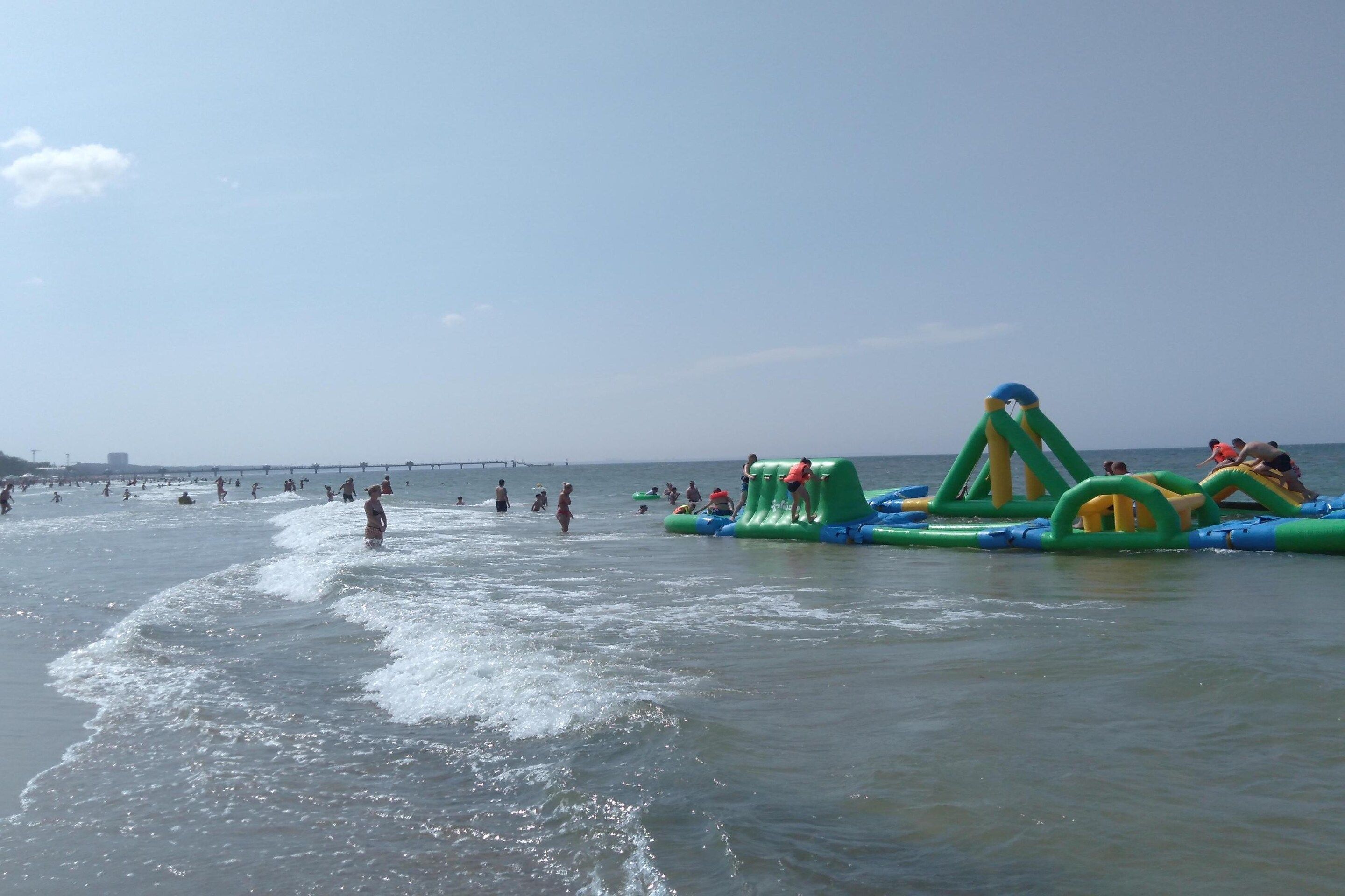 A beach with inflatable play structures and people swimming and playing in the water.