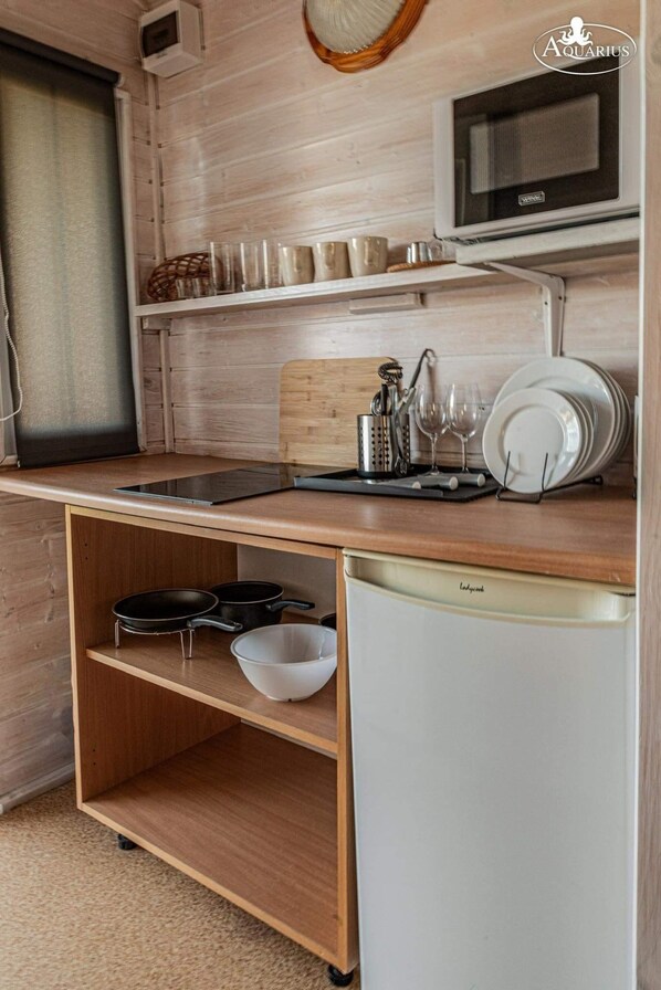 Uma cozinha compacta com micro-ondas, pia pequena e escorredor de louça.