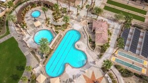 An aerial view of a resort with multiple swimming pools, a star-shaped sun patio, and a parking area. - Cozy 1-bedroom condo in terrific Palm Desert with AC and gym (Palm Desert)
