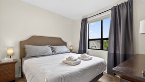 Een hotelkamer met een bed, nachtkastjes, een bureau en een raam met gordijnen.