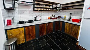A kitchen with a stove, sink, and wooden cabinets. - Apartment no. 5 (Antsiranana)