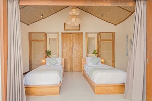 A bedroom with two wooden beds, a ceiling fan, and a wooden door. - Gapura (Pecatu)