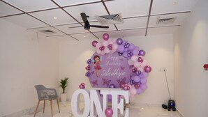 Ein Zimmer mit Geburtstagsdeko, Deckenventilator, Blumentopf und einem großen Schild mit der Aufschrift 'ONE'.