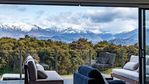 Ein Balkon mit Blick auf schneebedeckte Berge, einer Couch und einem Sessel.