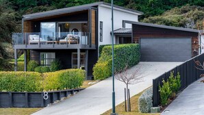 Ein modernes, zweistöckiges Haus mit Balkon, Garage und einem gepflegten Garten.