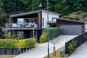 Ein modernes, zweistöckiges Haus mit Balkon, Garage und einem gepflegten Garten.