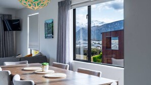 Ein modernes Zimmer mit einem großen Fenster, einem Esstisch und einem Fernseher.