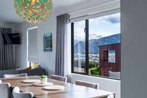 Ein modernes Zimmer mit einem großen Fenster, einem Esstisch und einem Fernseher.