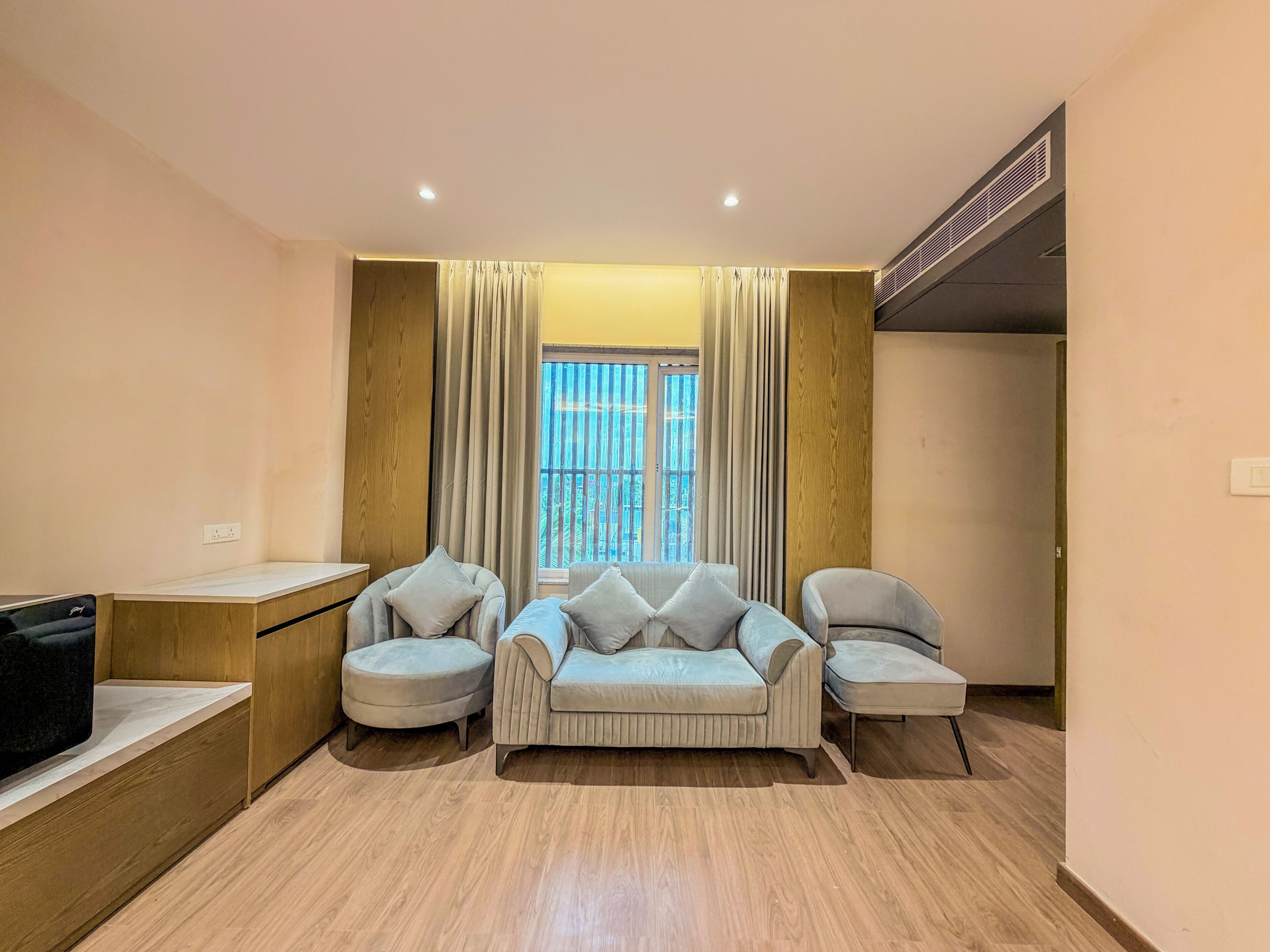 A modern living room with a sofa set, a TV, and a window with curtains.
