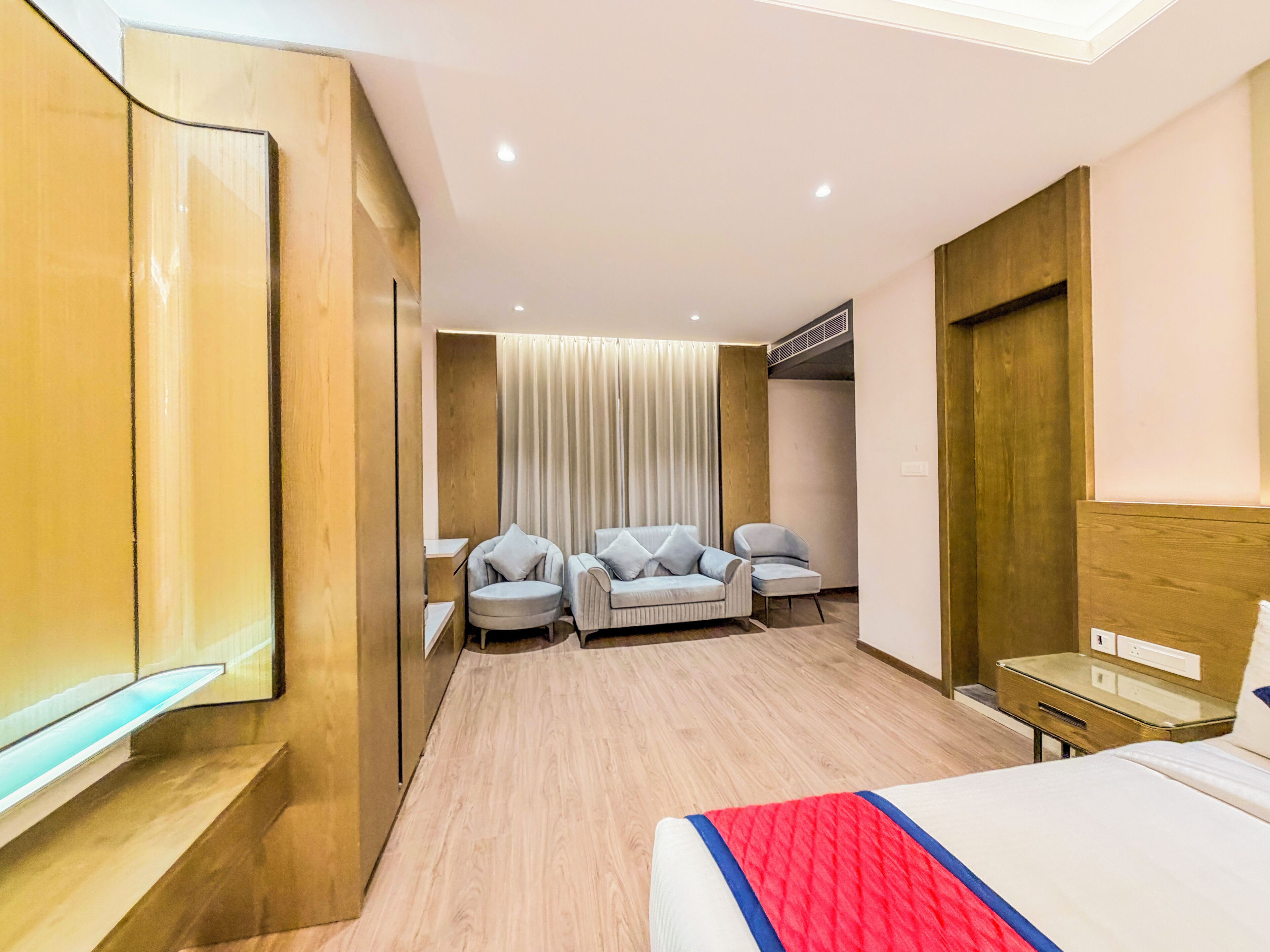 Ein modernes Hotelzimmer mit einem Bett, zwei Sesseln, einem kleinen Tisch und einem Spiegel.