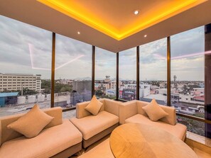 A modern interior with a sofa set and large windows offering a city view. - Jain Tree by Spree Hotels Vellore (Katpadi)